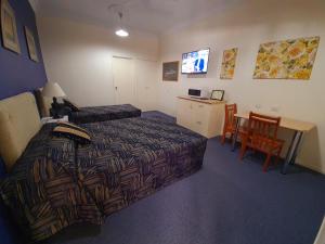 a hotel room with a bed and a table and a television at Criterion Hotel-Motel Rockhampton in Rockhampton