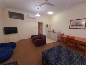 a living room with a couch a table and a television at Criterion Hotel-Motel Rockhampton in Rockhampton