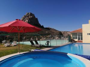 a pool with a red umbrella and a mountain at Hotel Quinta Las Fuentes Bernal in Bernal