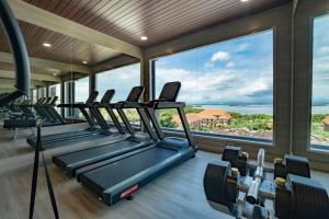 a gym with a row of treadmills and large windows at Sunrise Aventus Hotel Nusa Dua in Nusa Dua
