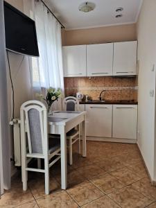 a kitchen with a white table and chairs and a tv at Apartament Spacerowa z balkonem in Kołobrzeg