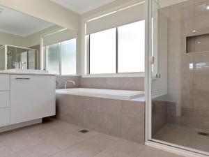 a bathroom with a tub and a shower with a window at Pollys in Callala Bay