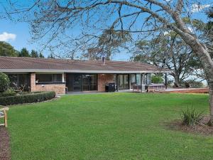 a brick house with a bench in a yard at Cooinda in Kangaloon