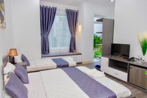 1 dormitorio con 2 camas, TV y ventana en Royal Hotel Ninh Thuận, en Kinh Dinh