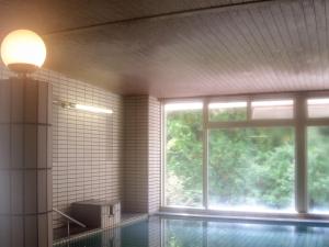 a room with a swimming pool and a large window at Hotel Nosegawa in Nosegawa