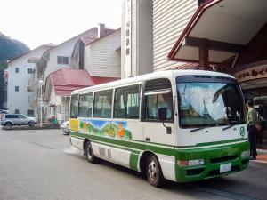 een groene en witte bus geparkeerd voor een gebouw bij Hotel Nosegawa in Nosegawa