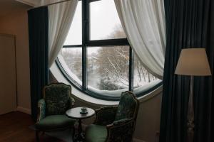 イジェフスクにあるエトノコンプレックス ボブロワヤ ドリーナの椅子2脚と大きな窓が備わる客室です。