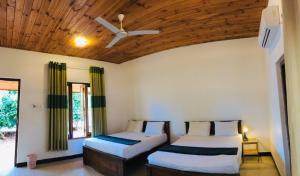 una camera da letto con due letti e un ventilatore a soffitto di ITALIAN GUEST a Trincomalee
