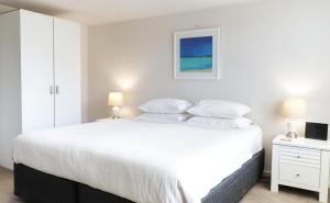 ein Schlafzimmer mit einem großen weißen Bett und einem weißen Schrank in der Unterkunft Fiveways Balcony, King Bed, Chef's Kitchen in Fremantle