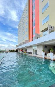 a swimming pool in front of a building at HARRIS Hotel Samarinda in Samarinda