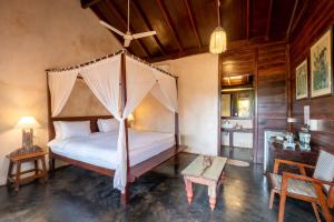 a bedroom with a canopy bed and a table at The Artist Cottages in Morjim