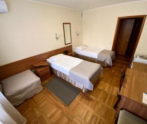 two beds in a room with wooden floors at Hotel Oktyabrskaya in Ulyanovsk