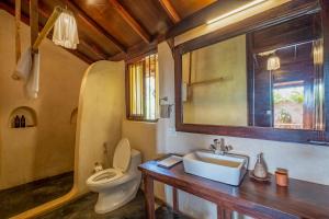 a bathroom with a toilet and a sink and a mirror at The Artist Cottages in Morjim