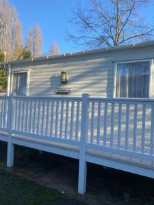 a white trailer with a fence on a yard at Kellys Holiday Homes 24 Willerby 2 bedrooms caravan in Weeley