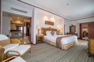 a hotel room with a large bed and two chairs at Waterfront Airport Hotel and Casino in Mactan