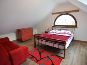 a bedroom with a bed and a red couch at holiday home, Swibno in Świbno