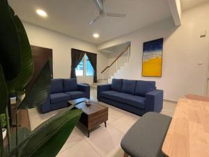 a living room with blue couches and a table at Golden Hill Home by Dreamscape in Cameron Highlands