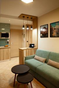 ein Wohnzimmer mit einem grünen Sofa und einem Tisch in der Unterkunft Designer apartments close to the center + free parking in Thessaloniki