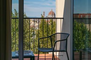 a chair sitting on a balcony looking out the window at B&B Hotel Firenze City Center in Florence