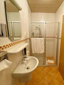 La salle de bains blanche est pourvue d'un lavabo et d'une douche. dans l'établissement Restaurant - Garni bei Peppo, à Ebern