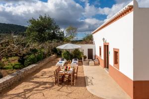 eine Terrasse mit einem Tisch, Stühlen und einem Sonnenschirm in der Unterkunft Villa Can Cova Camp in Sant Antoni de Portmany