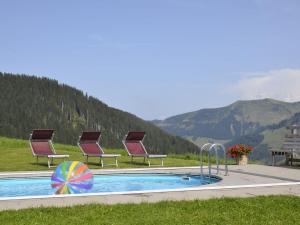 una piscina con sillas, una mesa y montañas en Comfortable Apartment in Dam ls with Swimming Pool, en Damüls