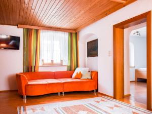 an orange couch in a living room with a window at Scenic Apartment in Rattenberg near Reintaler See Lake in Rattenberg