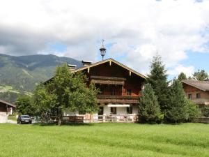 ein großes Holzhaus auf einem Feld mit Bergen in der Unterkunft Serene Cottage in Neukirchen am Gro venediger in Neukirchen am Großvenediger