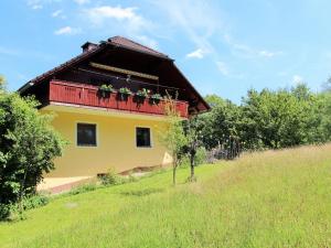 uma casa amarela com uma varanda vermelha numa colina em Apartment in Koettmannsdorf near bathing lake em Wurdach
