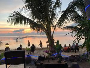 un grupo de personas en la playa al atardecer en Free Concept Beach Resort, en Srithanu