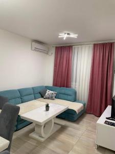 a living room with a blue couch and a table at Apartman SIMS in Bijeljina