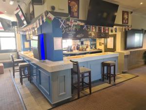 a bar in a restaurant with stools and flags at The Swan Hotel in Milton Keynes
