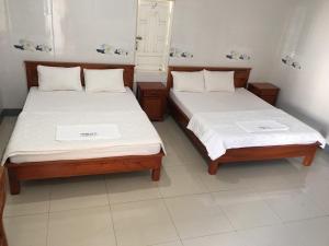 two beds sitting next to each other in a room at Nhà Nghỉ TRẦN ĐỨC in Phú Mỹ