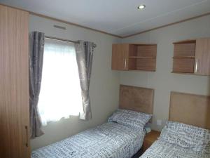 1 dormitorio con 2 camas y ventana en Bude Coastal Lodge, en Bude