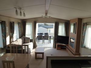 a living room with a couch and a tv and a table at Bude Coastal Lodge in Bude