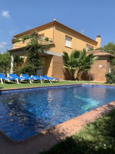 une piscine en face d'une maison avec des chaises et une maison dans l'établissement Villa Dacar, à Cubelles