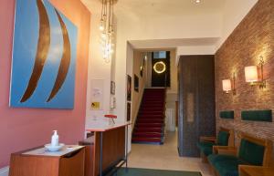 a hallway with a staircase and a lobby with green chairs at Hotel Union in Offenburg