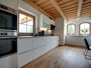 Il comprend une cuisine avec des placards blancs et un plafond en bois. dans l'établissement Holiday home in ski area in Mauterndorf with sauna, à Begöriach
