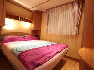 a small bedroom with a bed with a pink blanket at Mobile home near Lake Klopeiner See in Sankt Kanzian
