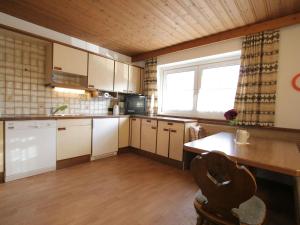 eine Küche mit weißen Schränken, einem Tisch und einem Fenster in der Unterkunft Beautiful Holiday Home near Ski Area in Ellmau in Ellmau