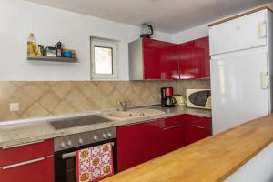 a kitchen with red cabinets and a white refrigerator at Bungalow am Wassergrundstück in Wendisch Rietz