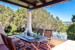 a wooden table and chairs on a patio with trees at SARDINIA RE - Villa Pelosa in Stintino