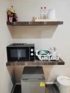 un microondas sentado en un estante en una cocina en We Resident Hotel en Hat Yai