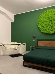 ein Schlafzimmer mit einem Bett und einer Badewanne neben einer grünen Wand in der Unterkunft B&B SOUL Messina in Messina
