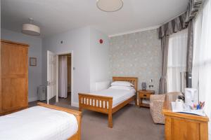 ein Schlafzimmer mit 2 Betten und einem Stuhl darin in der Unterkunft Lauriston Hotel in Weston-super-Mare