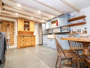 a kitchen with blue cabinets and a table and chairs at Trelash Cottage in Launceston