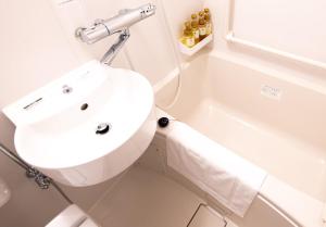 a white bathroom with a sink and a bath tub at Remington Hotel in Akashi