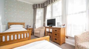 a bedroom with a bed and a tv and a chair at Lauriston Hotel in Weston-super-Mare