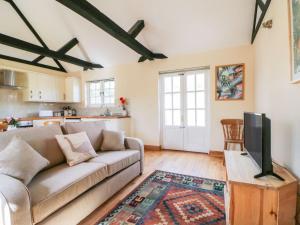 a living room with a couch and a tv at White Hart Stables in Battle