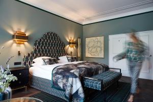 a woman running around a hotel room with a bed at Hotel Walther - Relais & Châteaux in Pontresina